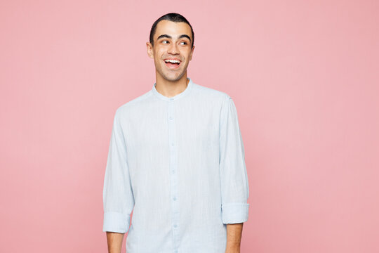 Young shocked amazed surprised fun impressed middle eastern man wear casual blue cotton shirt look aside on area isolated on plain pastel light pink wall background studio portrait. Lifestyle concept.
