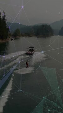 Vertical video: Boat moving, driver steering, rider wakeboarding for sport, overlay spanning scene