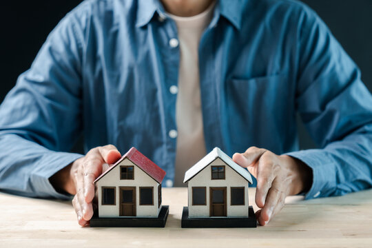 Real estate, property investment and mortgage concept. Person holding two model houses.