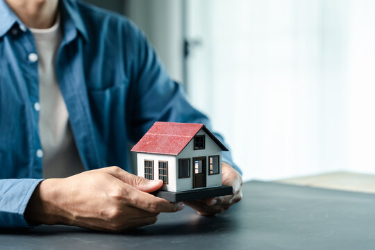 Real estate, property investment and home mortgage concept. Person holding model house.