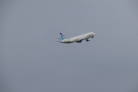 An Air Busan commercial airplane climbing into a hazy sky after takeoff.