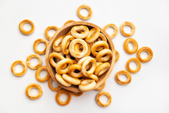 Small bagels in wooden bowl on white background, top view. Freshly baked round mini buns, dry cookies for tea, delicious flour-based pastries