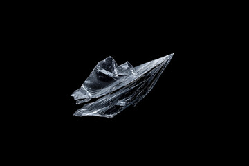 Naklejka premium Abstract sharp transparent glass shard floating on a black background, with bright reflections, fractured edges, and a dramatic minimalist studio look.