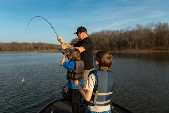 Young boy catching a fish while on a boat with his family