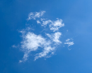 Obraz premium Isolated cascading cloud floating in the wind against blue cirrus sky. Big glowing clouds spreading on the deep blue sky sunny day. Nature concept background. Elegant landscape image