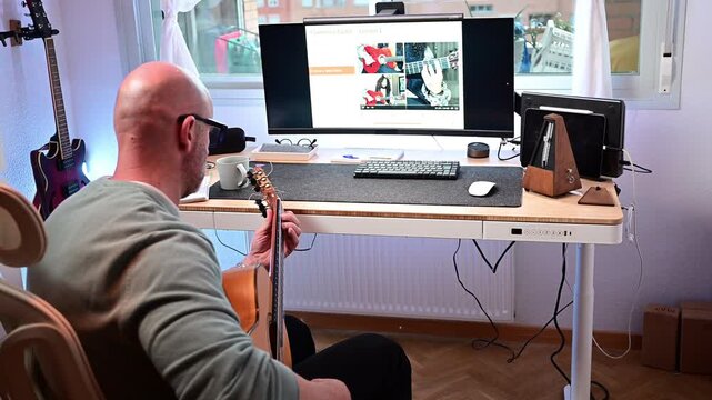 Man taking online guitar lessons at home