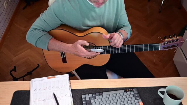 Mature musician restringing and tuning classical guitar at home