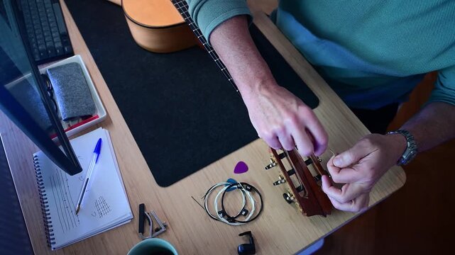 Musician changing strings on a classical guitar