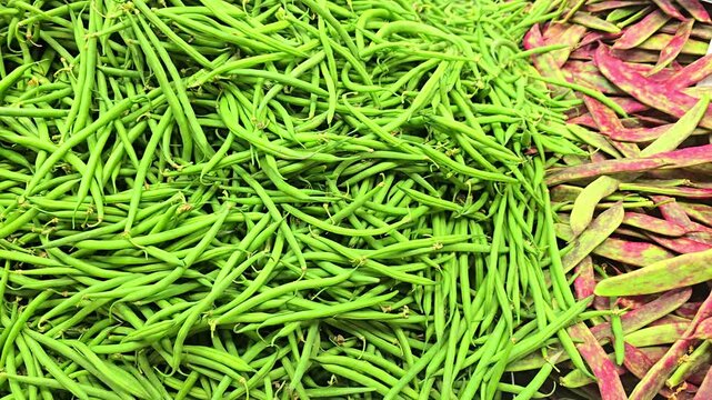 Close up shot of fresh green beans on a market stall as camera slowly moves closer, showing bright color, crisp texture and natural produce, capturing healthy food and vibrant market atmosphere.