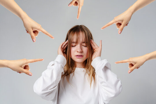 Girl holding her head with hands pointing at her in a simple studio setting