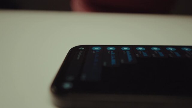 Finger touching play button on smartphone screen to listen to voice message, with audio waveform visualizing sound as it plays through chat application, close-up. Shooting in slow motion.