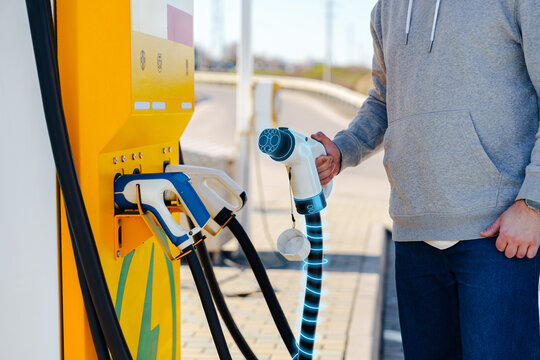 Charging an electric car at a public station during daylight in a busy area