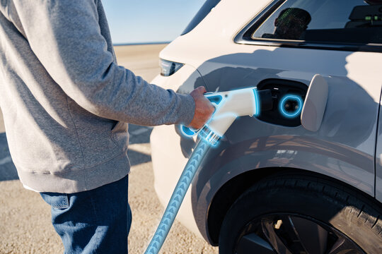 Electric car charging station in use by a man on a sunny day