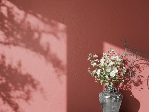 Muted red wall with white flowers in a vase and artistic tree branch shadows.