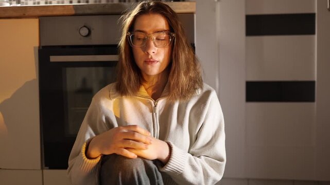 Young woman sitting alone in kitchen trying to stay away from smartphone resisting привычка scrolling and learning to focus on real life in quiet evening home atmosphere