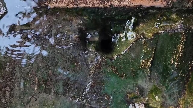 Close up of water flowing into the gap in the drain hole