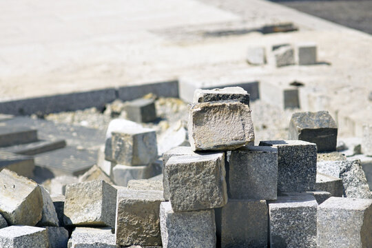 Granite paving cubes stacked after sidewalk dismantling on street renovation site. Represents municipal asset recovery, durable material recirculation, and cost-efficient public realm modernization.