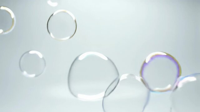 Transparent, perfectly spherical, iridescent soap bubbles gracefully float and gently pop in slow-motion against a pure white, seamless background with high-key lighting. Concept of purity and gentle