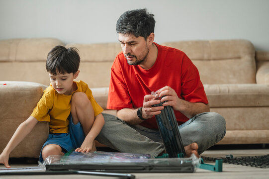 Father helping son assemble furniture together in the living room