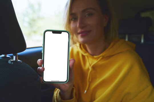 Passenger in car showing smartphone with blank screen mockup