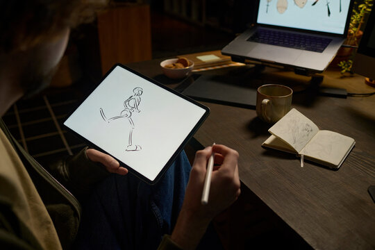 Digital artist drawing on graphics tablet at indoor desk at night