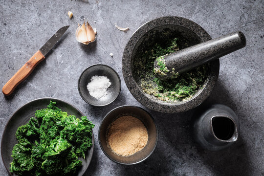Preparing healthy vegan homemade kale pesto on grey countertop
