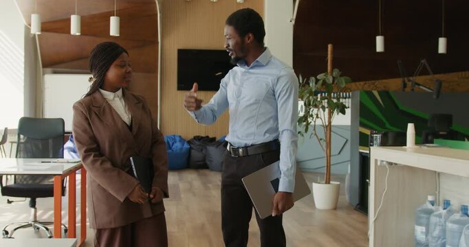 Black coworkers sharing light moment in coworking office black man