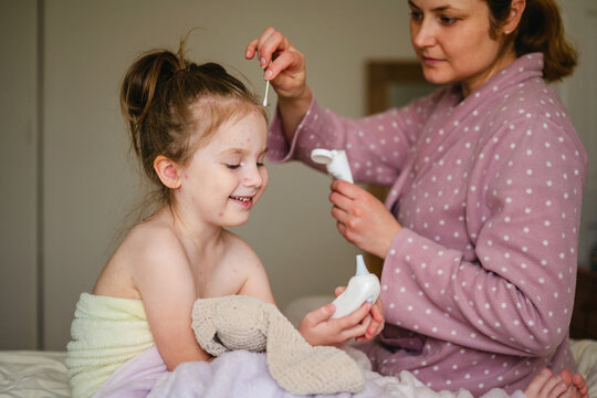 Mother applying chickenpox gel to smiling family member