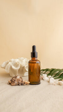 Amber glass dropper bottle with natural elements on sandy beach background