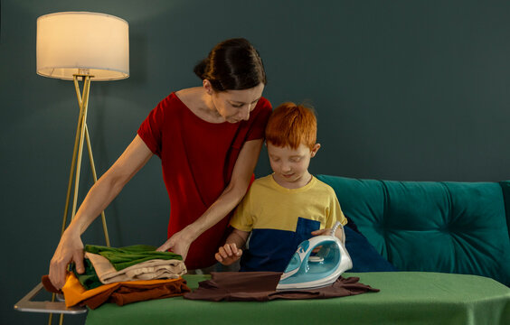 Mother and son ironing together at home in the evening