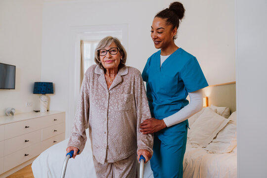 Caregiver assisting senior with walker in home bedroom