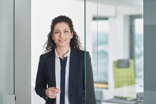 Happy mature businesswoman standing in office doorway