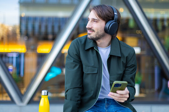Commuter listening to music on smartphone outdoors in city