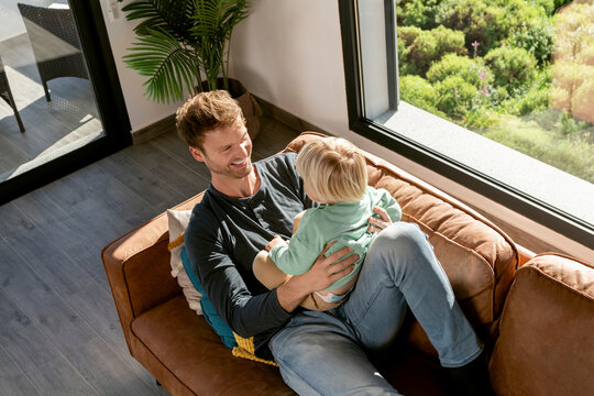 Happy father playing with son on sofa at home