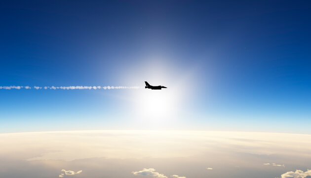 Fighter jet silhouette flying high in blue sky with contrail