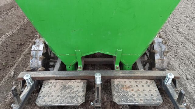 Modern Green Potato Planter Machine Working on Freshly Cultivated Soil ensures efficient planting. This agricultural equipment precisely opens furrows in the ground. It is essential for farm work