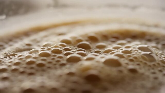 Close up macro shot of frothy beverage bubbles with a light brown hue, creating a textured surface