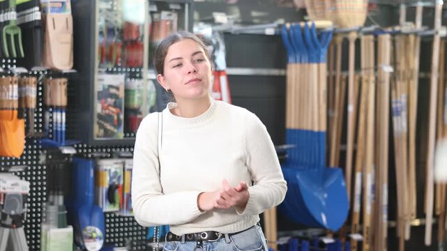 Young woman choosing tools for gardening. Customer came to the sale in the garden section of the supermarket. High quality 4k footage