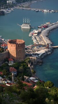 Panoramic aerial view of Alanya harbor with Red Tower and Seljuk Shipyard in Turkey. Scenic Mediterranean cityscape, historical fortress, ancient shipyard and Turkish Riviera travel concept