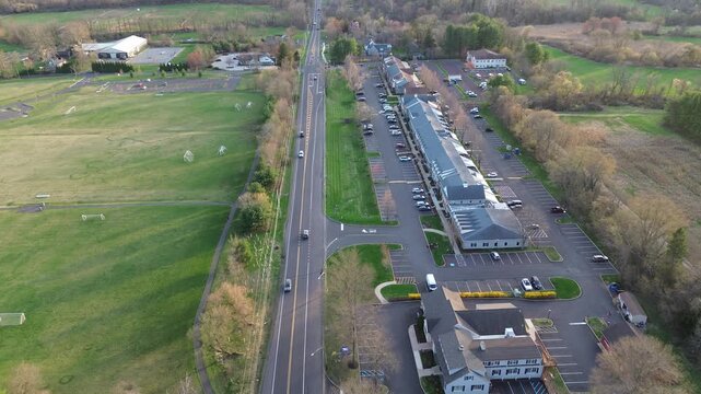 Soccer fields along Buckingham Township corridor sit beside York Rd with commercial buildings lining opposite side. Open turf, bare trees, gentle midday lighting form balanced semirural scene, PA