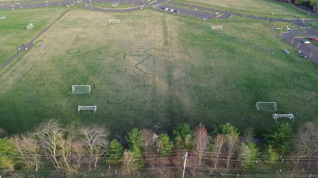 Recreation fields near Holicong Park sit along Buckingham Township corridor with York Rd access nearby. Patchy turf patterns, scattered goals, and soft seasonal lighting shape open textures in PA