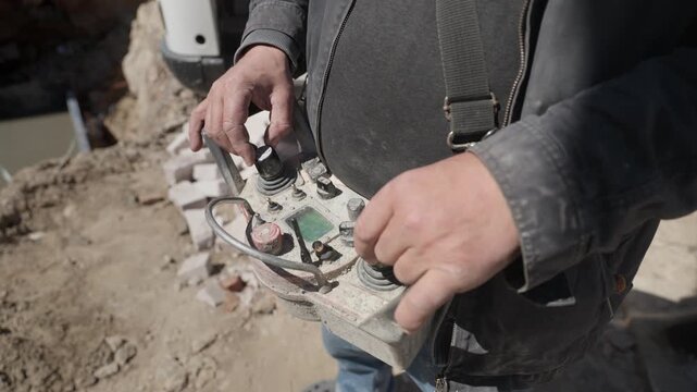 Professional operator managing a concrete pump at a construction site using a radio remote control, manipulating joysticks and buttons to precisely guide the industrial equipment during work