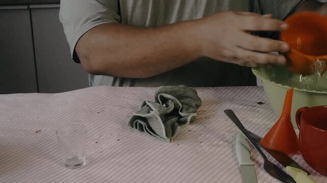 Male hands drying a spoon with a dishcloth.