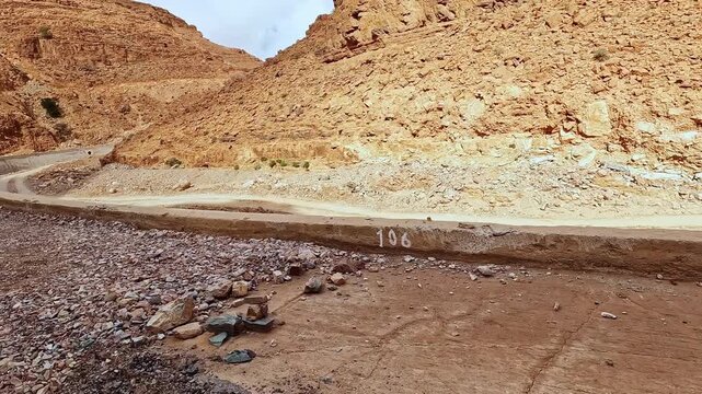 Road construction and repair work in a deep rocky canyon in morocco with damaged infrastructure and landslide debris