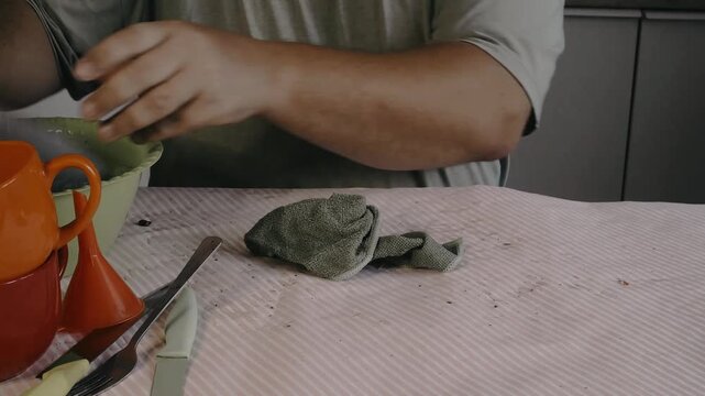 Male hands drying a spoon with a dishcloth.
