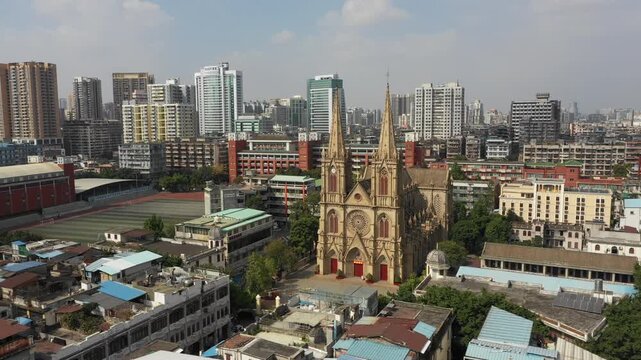 Rotating drone shot of gothic cathedral among residential apartment buildings and commercial office towers in Guangzhou, China
