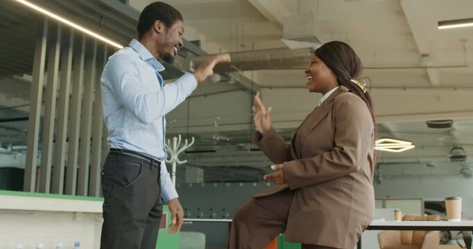 Black manager discussing project update with colleague in bright office