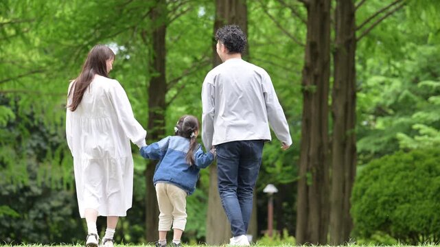 家族、新緑の公園で手を繋ぐ歩く幸せなファミリーライフスタイル動画　全身の顔無しの後ろ姿