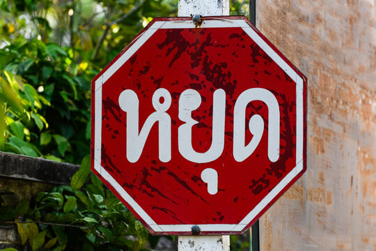 Internationally recognized red, octagonal stop sign with the word "stop" written in  the abugida script of the Thai language.