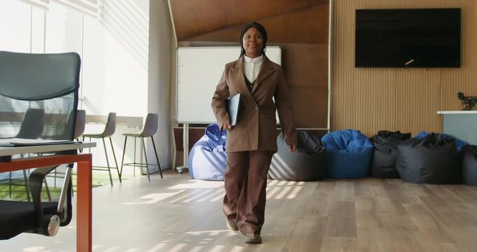 Black executive striding through openplan coworking office